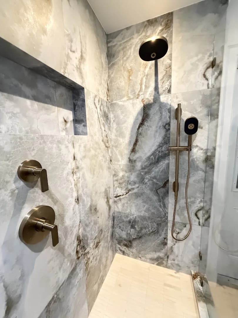 Walk-in shower with marble-look tile and brushed-gold rainfall and handheld